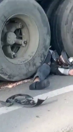 Motorcyclist's Body Mixed With The Wreckage Of His Helmet Under The Wheels Of A Truck