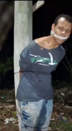 Beating A Man Tied To A Pole With A Club