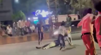 A Half-Naked Man Is Beating A Dude Lying In The Middle Of The Road With A Stone